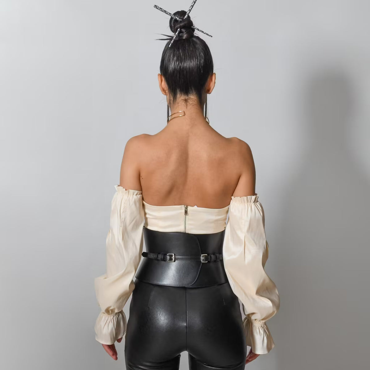 Aria Margo black leather V-cut corset belt worn over a cream off-shoulder top, showing a back view