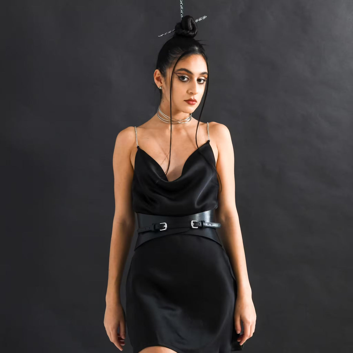 Aria Margo slim black Italian leather corset belt worn over a black satin dress by a mode