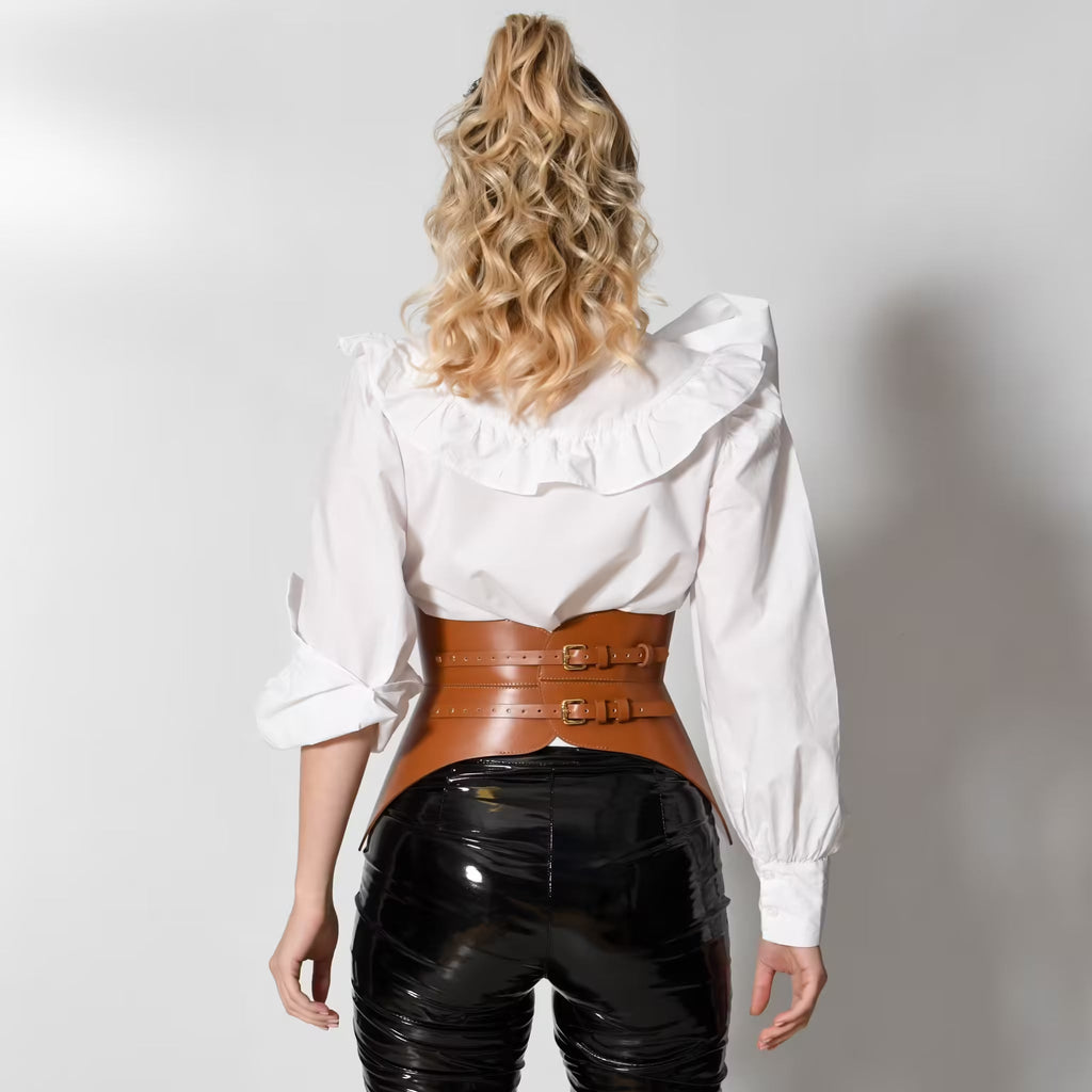 Aria Margo brown Italian leather corset belt with back buckles worn over a white ruffled blouse and black pants.