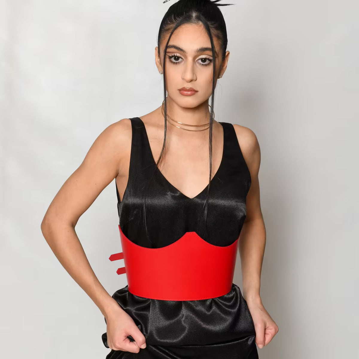 Aria Margo red Italian leather under-bust belt worn over a black satin dress by a model.