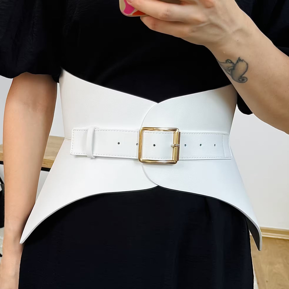 Aria Margo white Italian leather corset belt with a gold buckle worn over a black dress to define the waist.