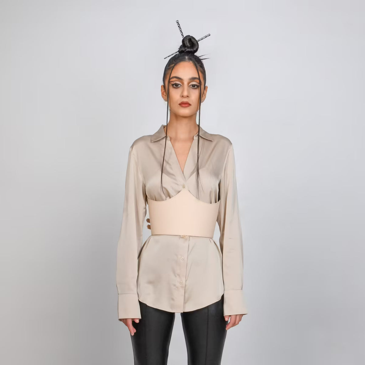 Aria Margo beige leather under-bust belt worn over a silk shirt, featuring adjustable buckles and sculpted fit.