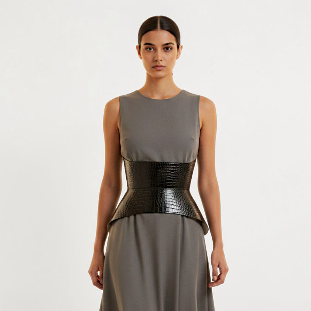 Aria Margo black croc-embossed leather corset belt worn over a grey sleeveless dress to define the waist.