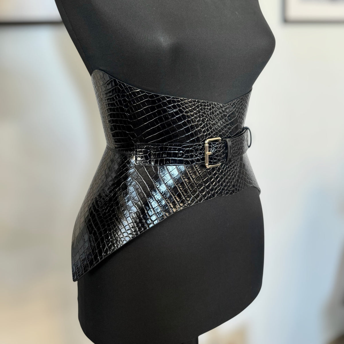 Aria Margo black croc-embossed leather corset belt with a single buckle, worn on a mannequin to shape the waist.