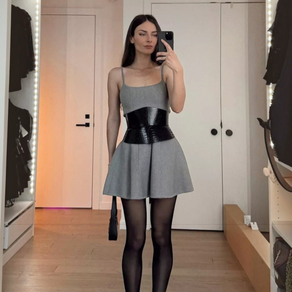 Aria Margo black croc-embossed leather corset belt worn over a grey mini dress by a woman in a mirror selfie