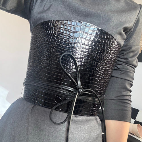 Aria Margo black croc-embossed leather corset belt with wrap-around cord lacing worn over a grey dress