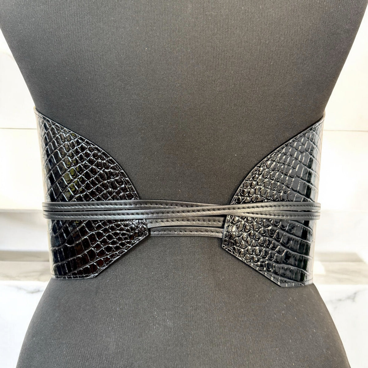 Aria Margo black croc-embossed leather waist belt with wrap-around cord lacing on a mannequin torso.