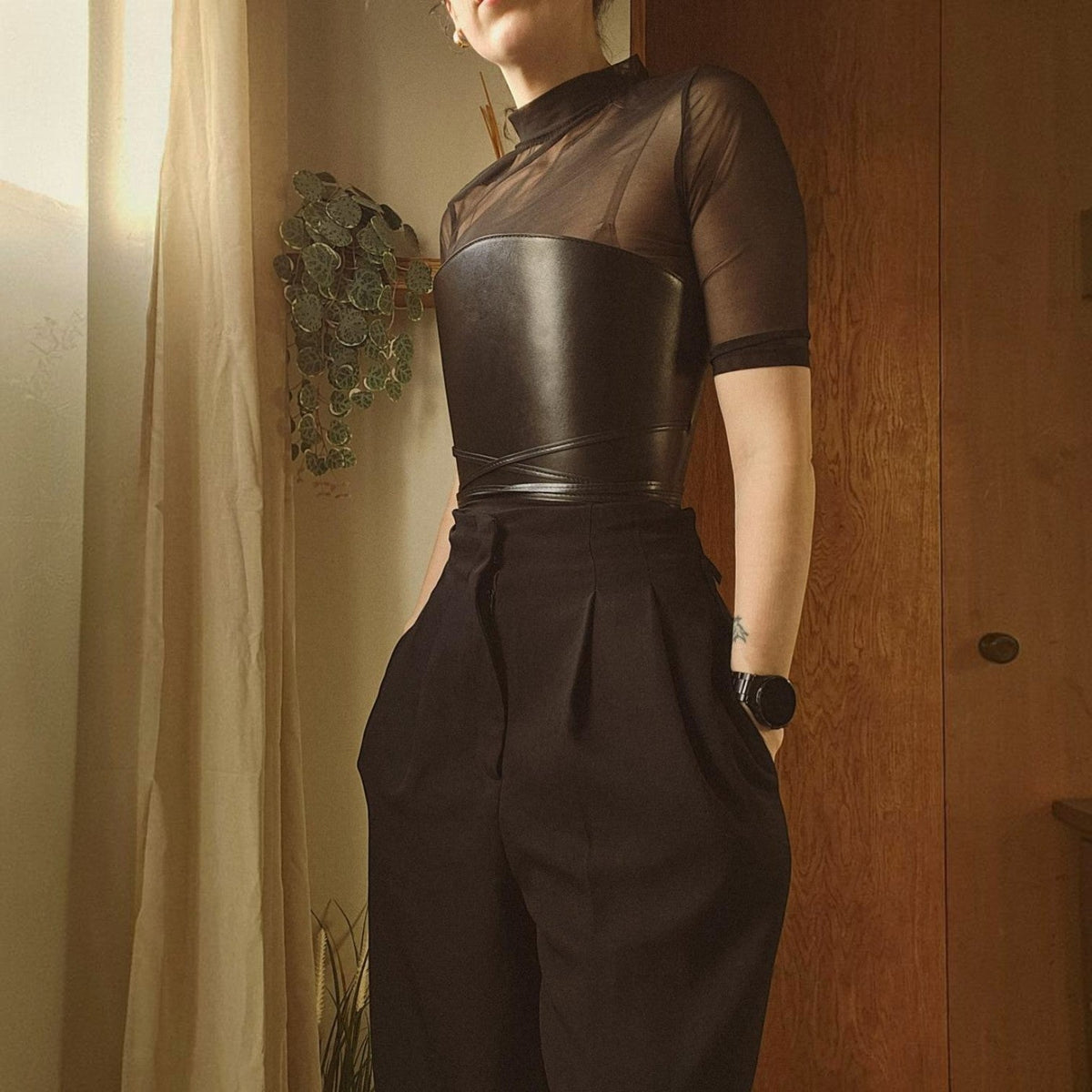Aria Margo black leather cord top belt worn over a sheer black top and trousers, featuring a wrap-around design.