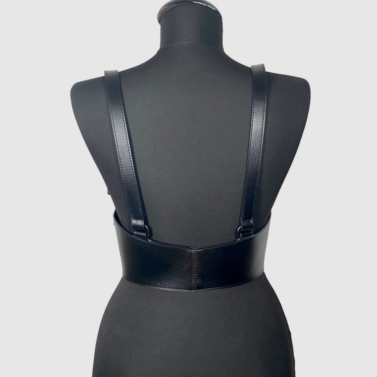 Aria Margo black Italian leather under-bust corset with adjustable shoulder straps on a mannequin, back view.
