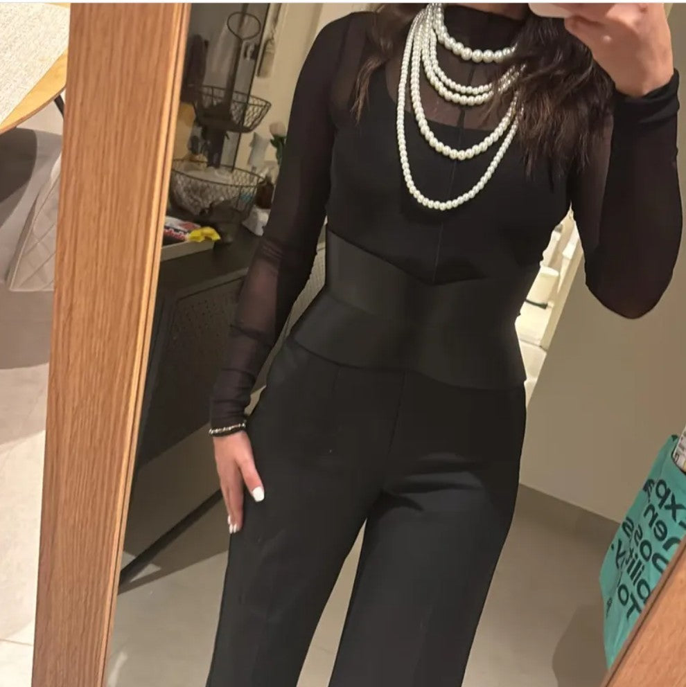 Aria Margo black leather hourglass corset belt worn over a black long-sleeve top and trousers in a mirror selfie