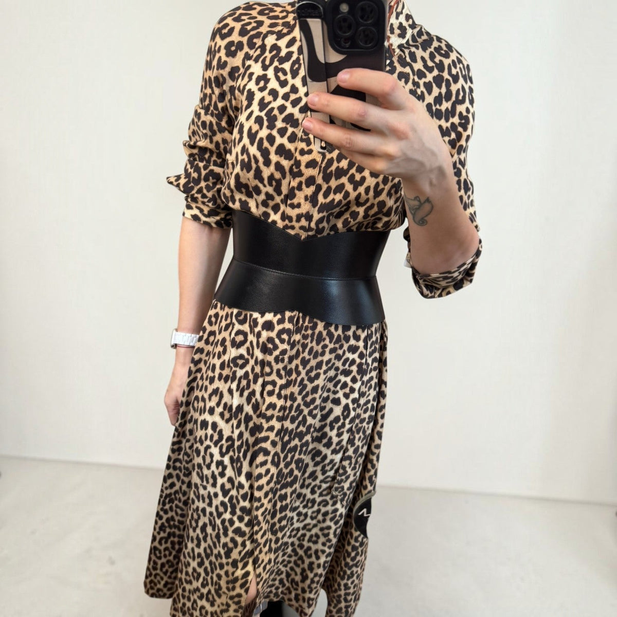 Aria Margo black leather hourglass corset belt worn over a leopard print midi dress for a defined waist shape