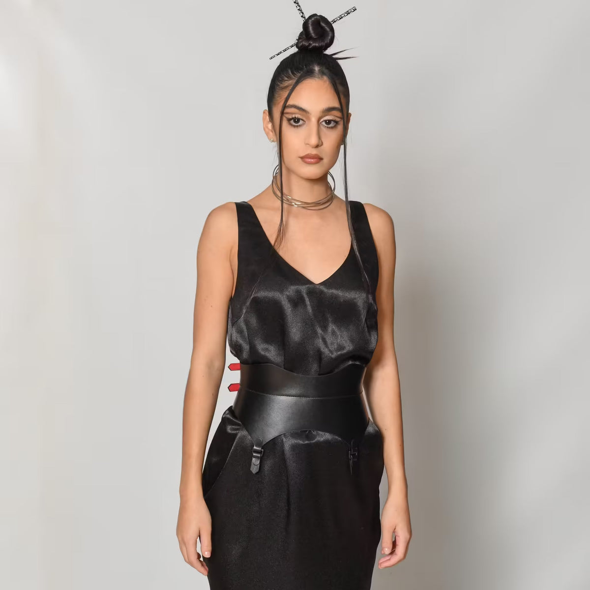 Aria Margo black leather corset belt with gold buckles and suspender-style tabs worn over a black satin dress