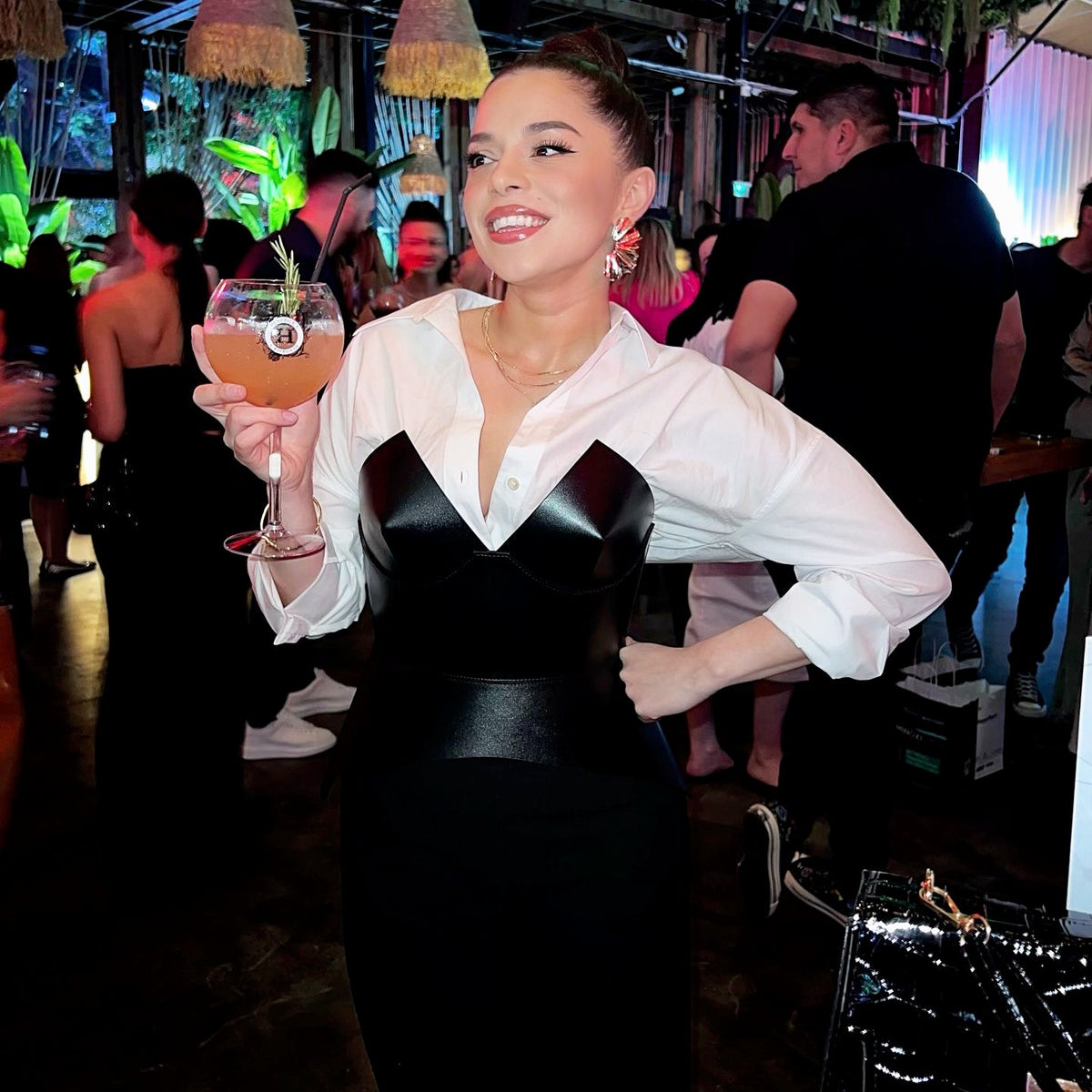 Aria Margo black leather full body corset belt worn over a white button-down shirt at a social event