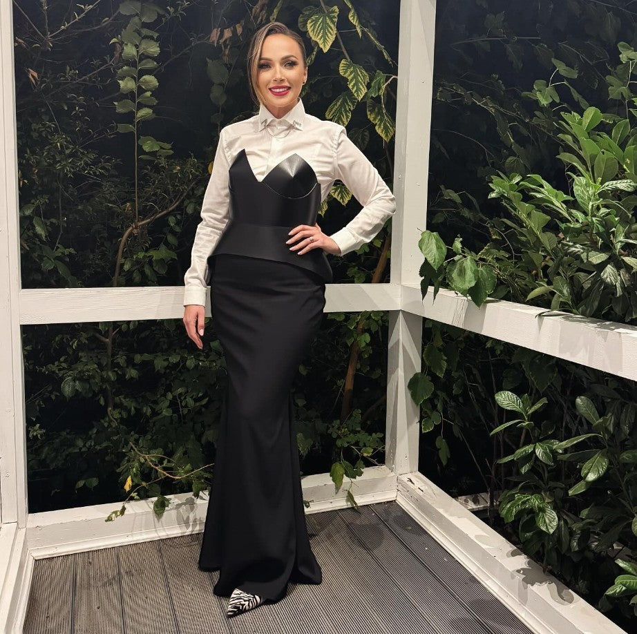 Aria Margo black leather full body corset belt worn over a white shirt and long black skirt for a chic look