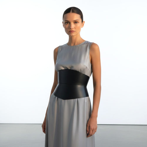 Aria Margo black leather corset belt worn over a grey sleeveless dress, creating an hourglass silhouette.