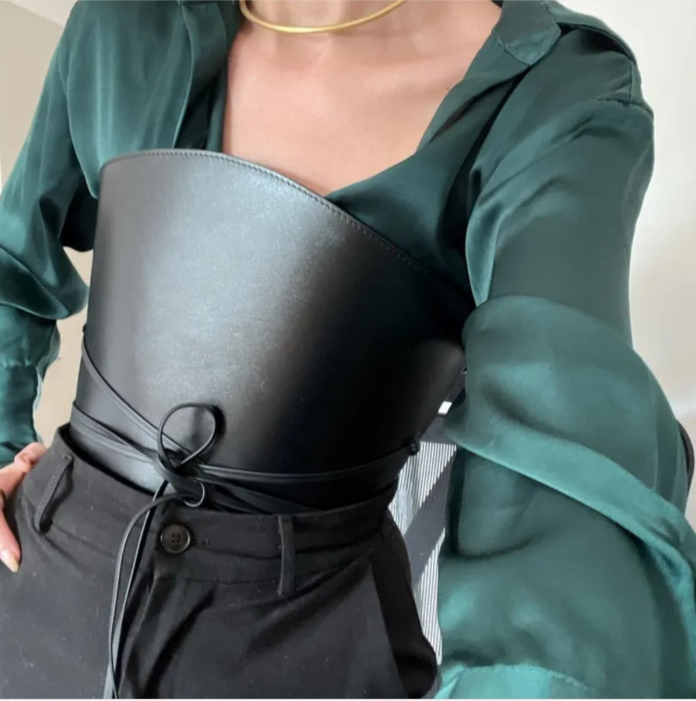 Aria Margo black leather corset-style waist belt with wrap-around cord detail worn over a green silk shirt.
