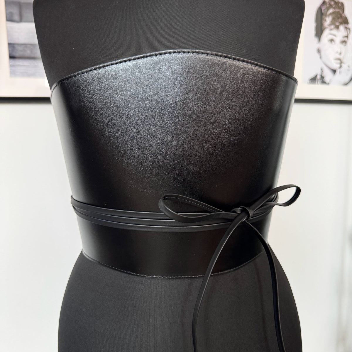 Aria Margo black leather corset belt with a wide structured design and long wrap-around cord tie on a mannequin.