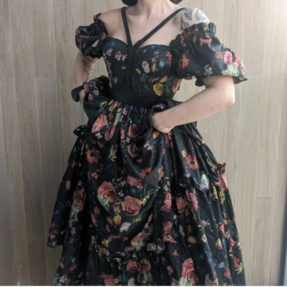 Aria Margo black leather V-neck harness belt worn over a floral off-the-shoulder dress for a statement look
