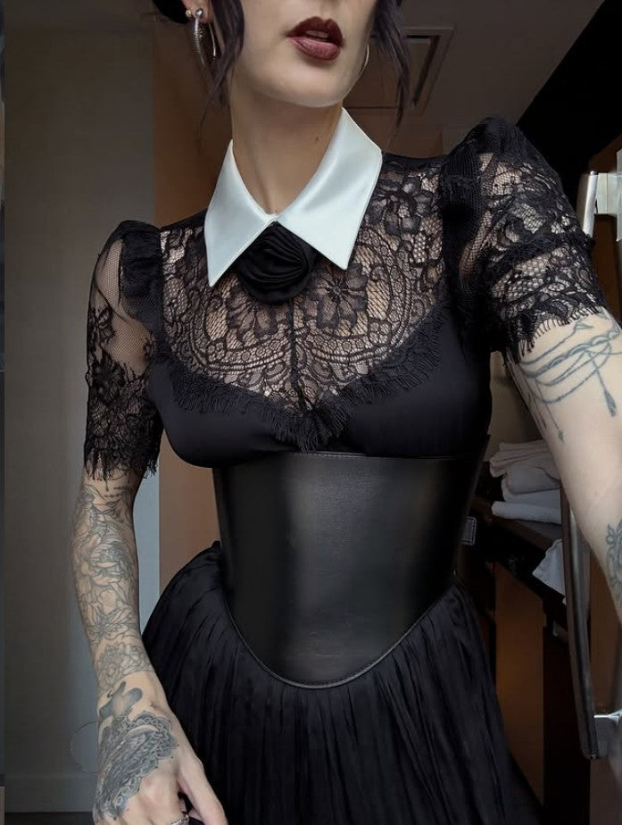 Aria Margo black leather under-bust belt worn over a black lace dress with a white collar