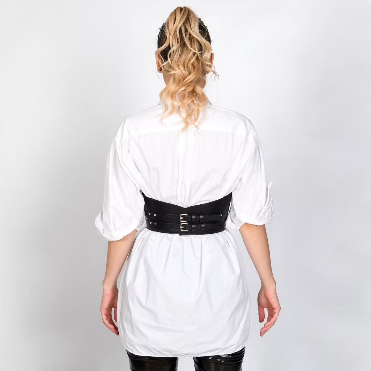 Aria Margo black leather under-bust belt with double buckles worn over a white shirt, back view.