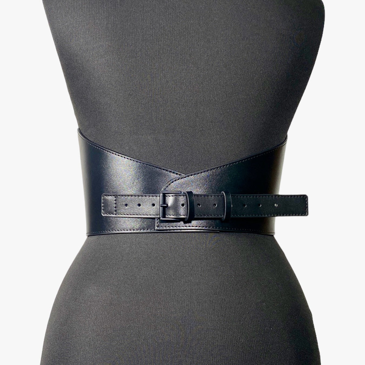 Aria Margo black Italian leather under-bust belt with a curved design and a sleek matching buckle on a mannequin.