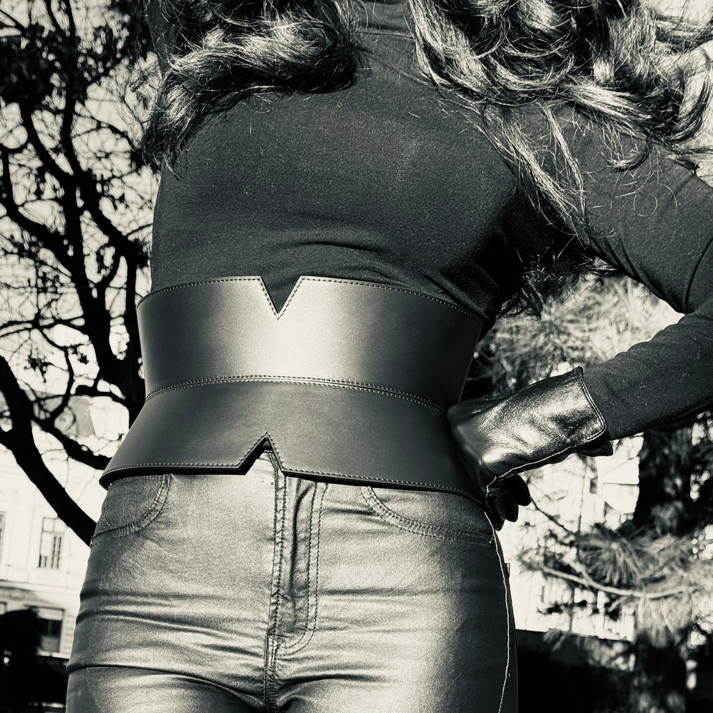 Aria Margo black leather V-cut corset belt worn over a black top and trousers to define the waistline