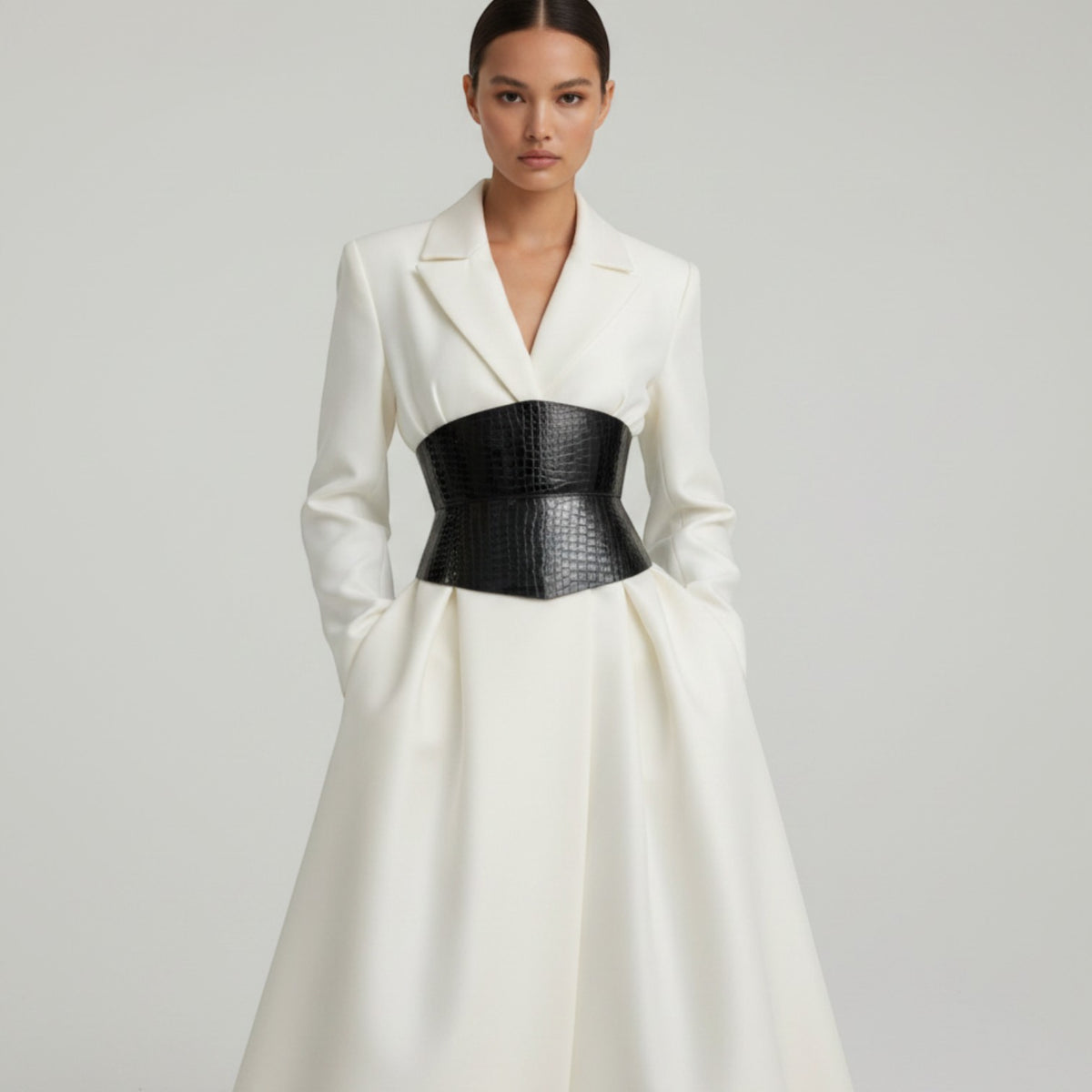 Aria Margo black patent croc-embossed leather corset belt worn over a white blazer dress for a defined waist.