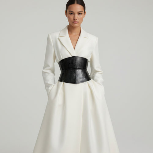 Aria Margo black patent croc-embossed leather corset belt worn over a white blazer dress for a defined waist.