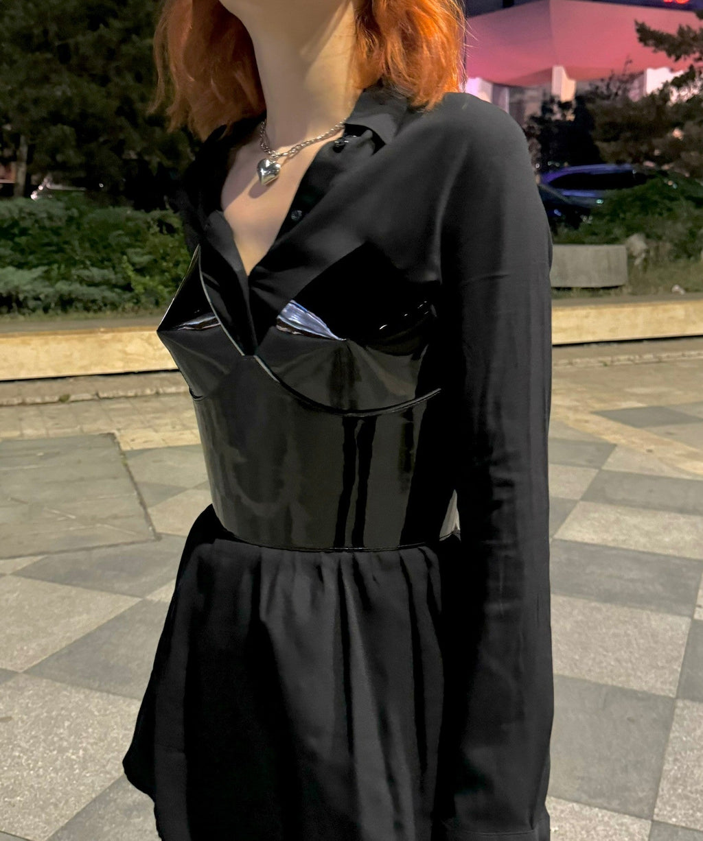 Aria Margo black patent leather over-bust corset worn over a black shirt, featuring a structured silhouette.