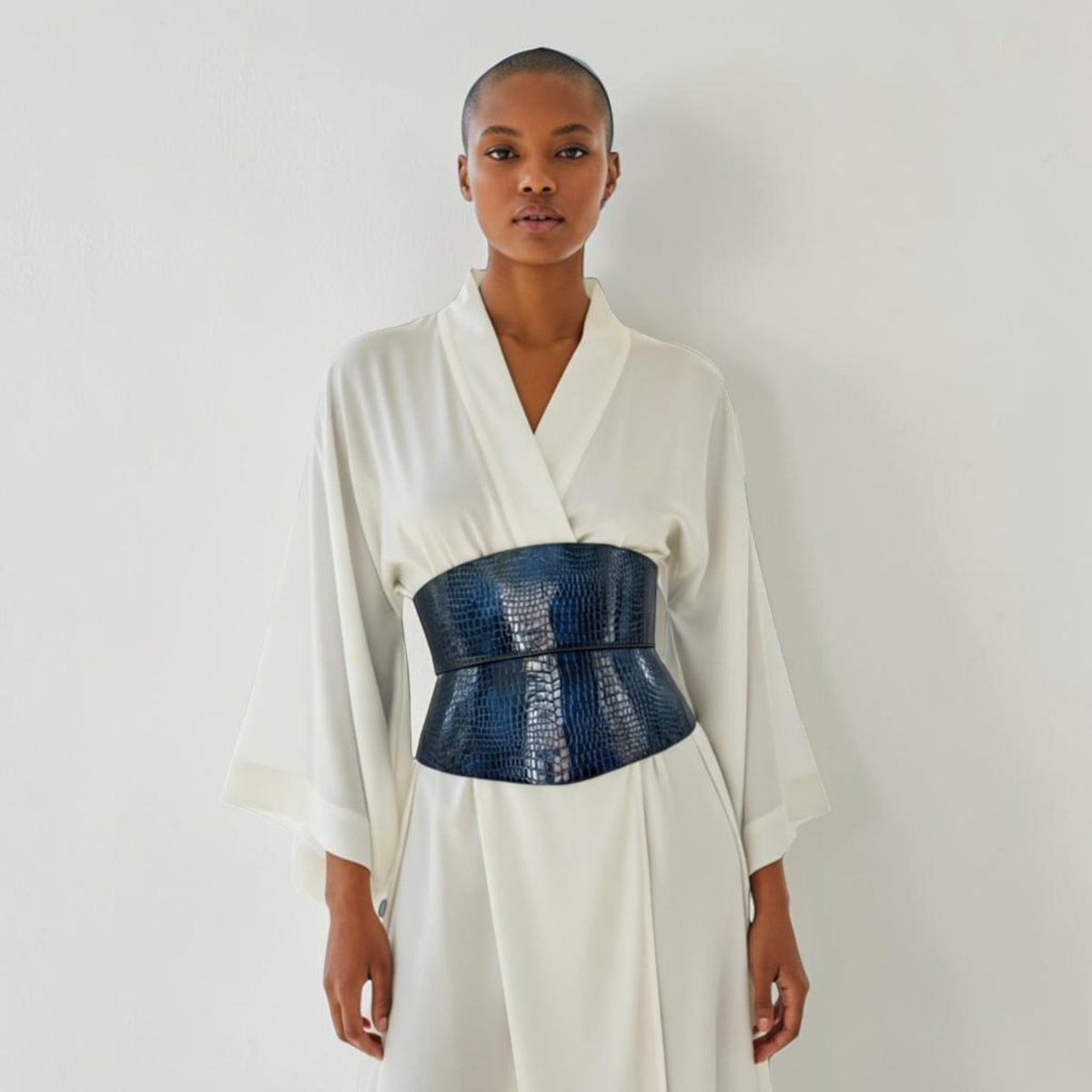 Aria Margo blue croc-embossed leather corset belt with black buckles worn over a white silk kimono dress