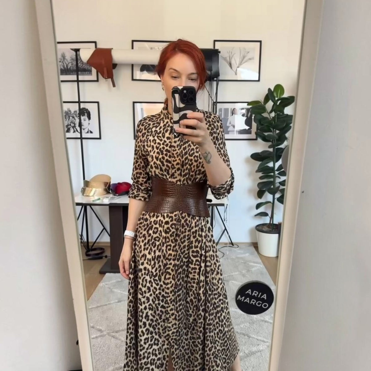 Aria Margo brown croc-embossed leather hourglass corset belt worn over a leopard print midi dress in a mirror