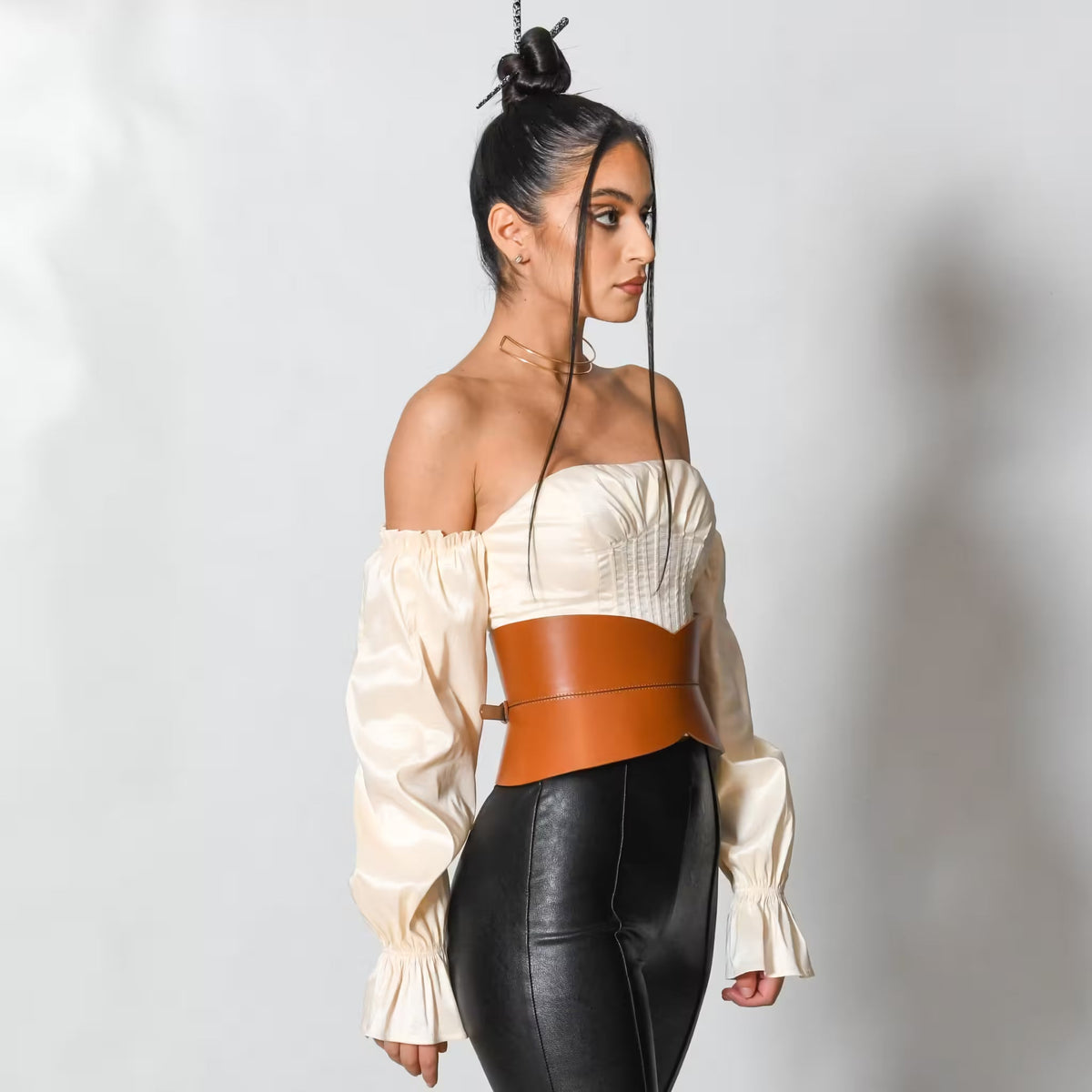 Aria Margo brown Italian leather hourglass corset belt worn over a cream off-shoulder top and black trousers