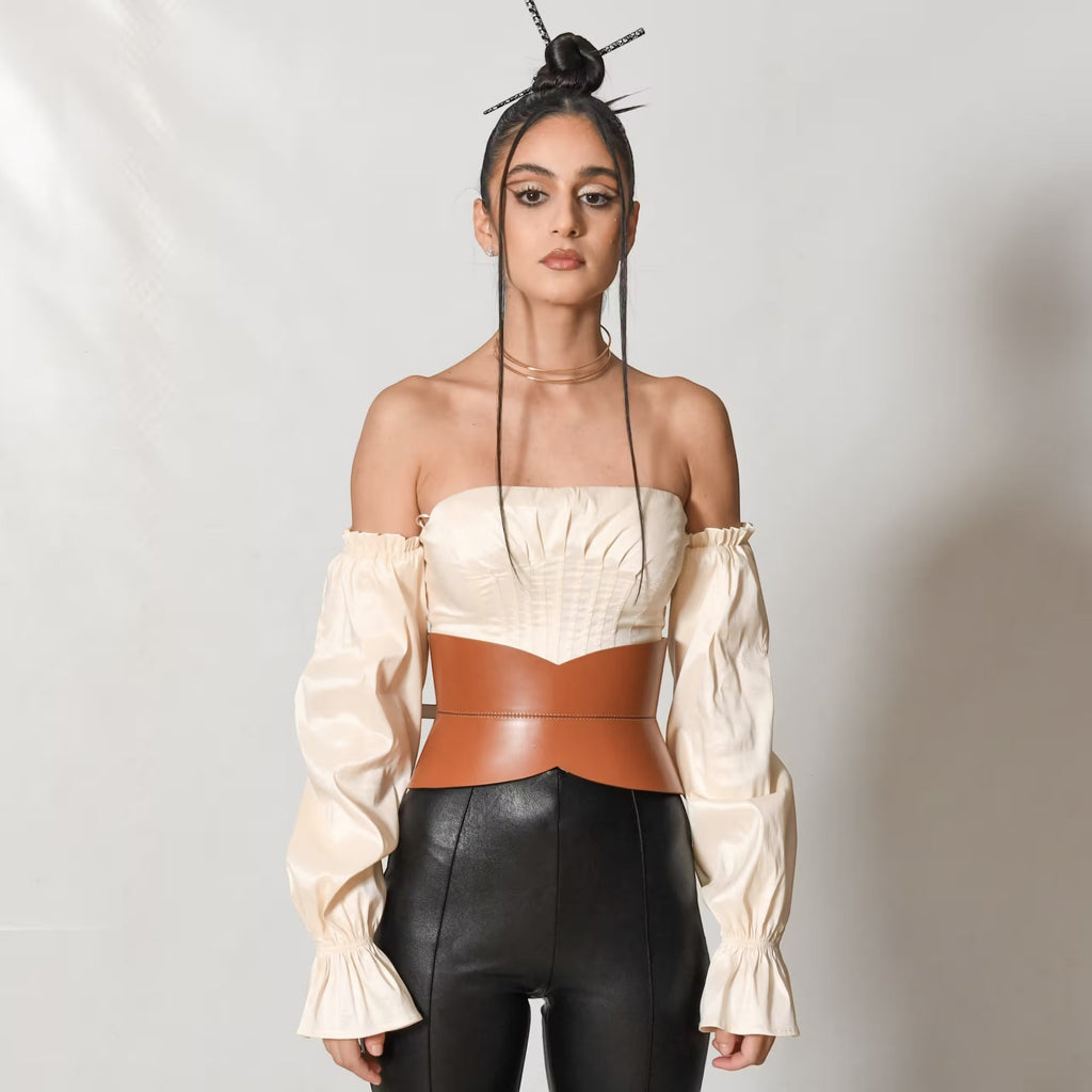 Aria Margo brown leather hourglass corset belt worn over a cream off-shoulder top and black trousers