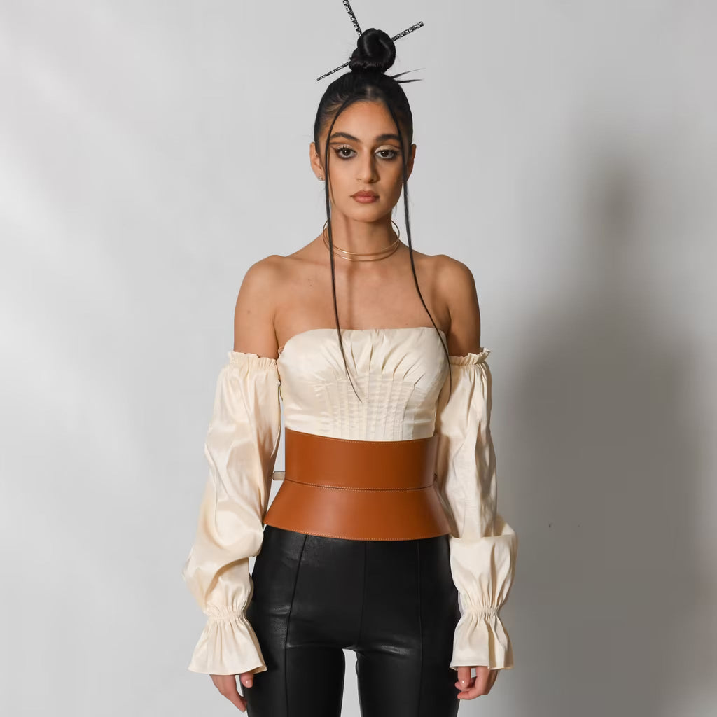 Aria Margo wide brown Italian leather corset belt worn over a cream off-shoulder top and black trousers