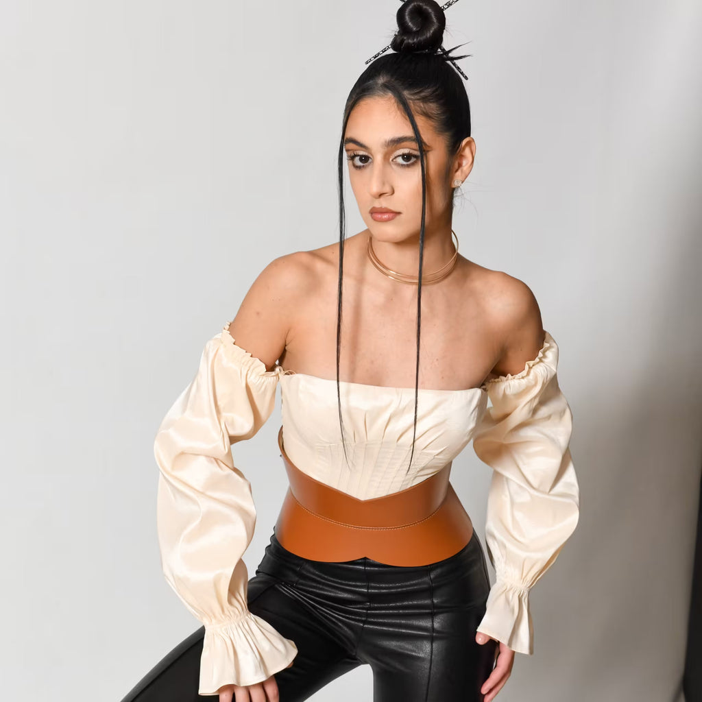 Aria Margo brown leather hourglass corset belt worn over a cream off-shoulder top and black trousers