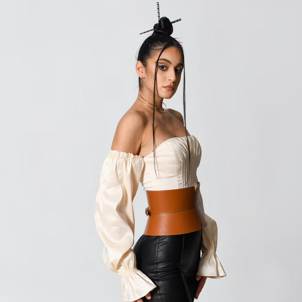 Aria Margo brown leather V-cut corset belt worn over a cream off-shoulder top and black trousers