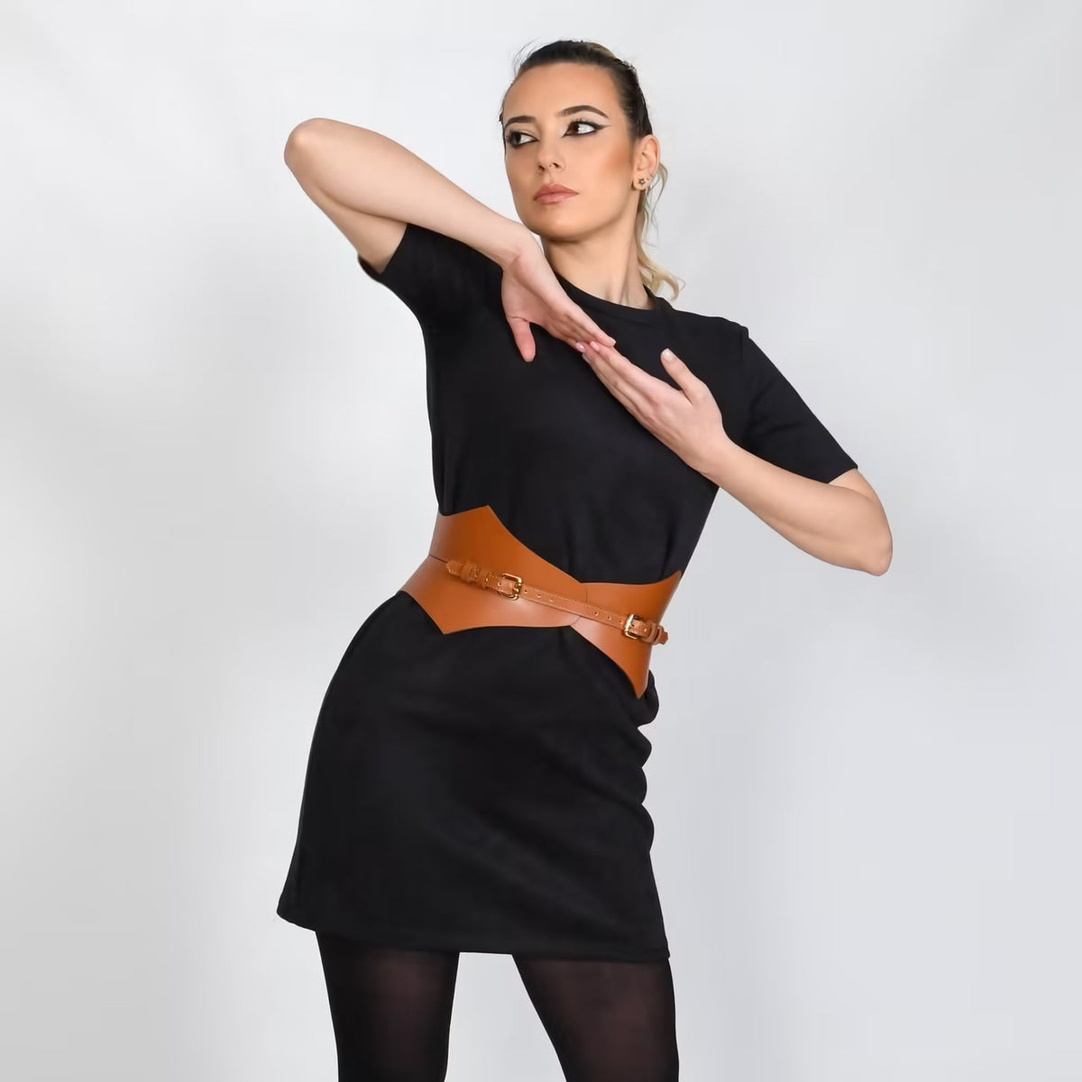 Aria Margo brown Italian leather corset belt worn over a black dress by a model posing against a white background