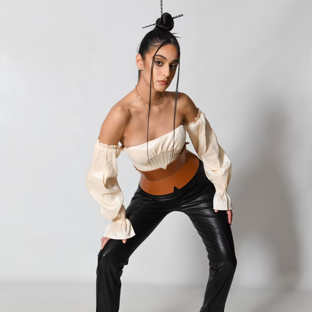 Aria Margo brown leather V-cut corset belt worn by a model in a cream off-shoulder top and black trousers