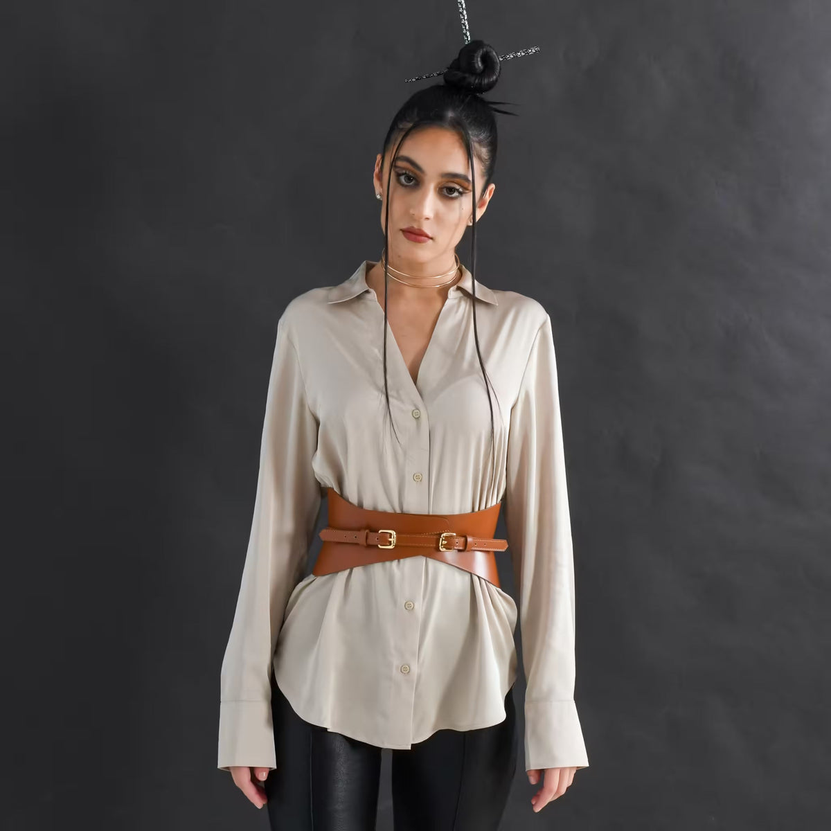 Aria Margo slim brown Italian leather corset belt worn over a beige button-down shirt for waist definition.