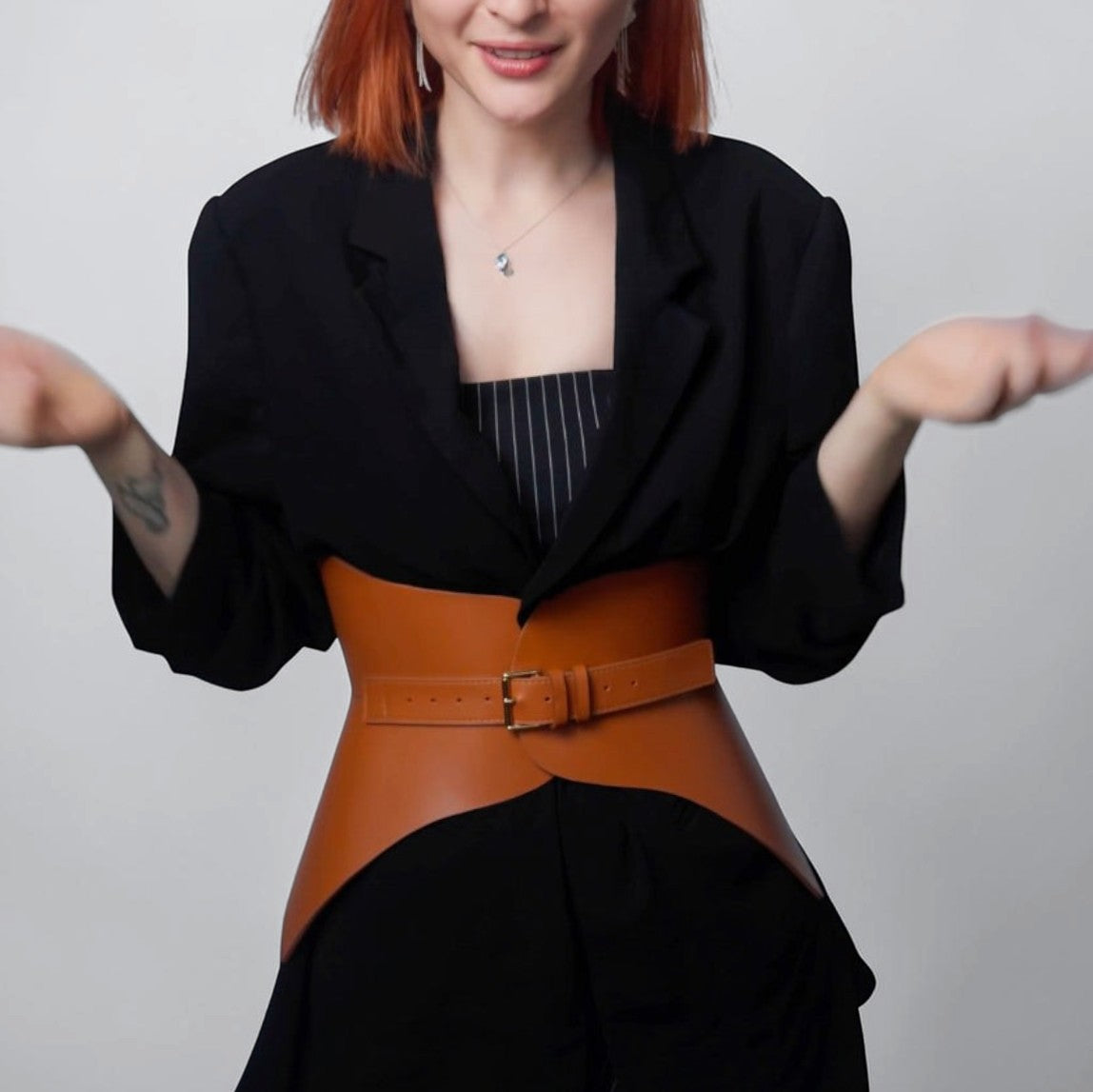 Aria Margo brown leather corset belt worn over a black blazer to accentuate the waist and hips.