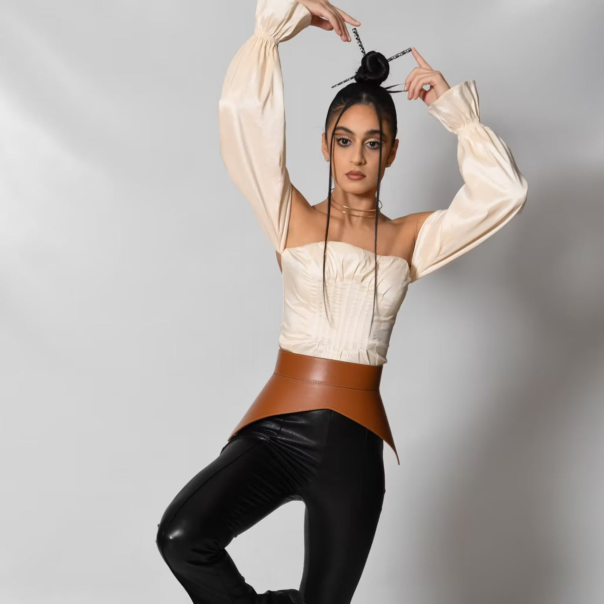 Aria Margo brown leather peplum corset belt worn by a model in a cream top and black trousers