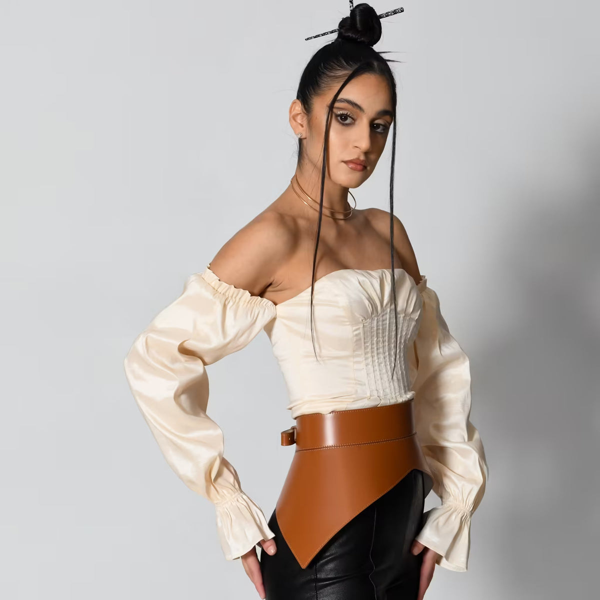 Aria Margo brown Italian leather peplum corset belt worn over a cream off-shoulder top and black trousers