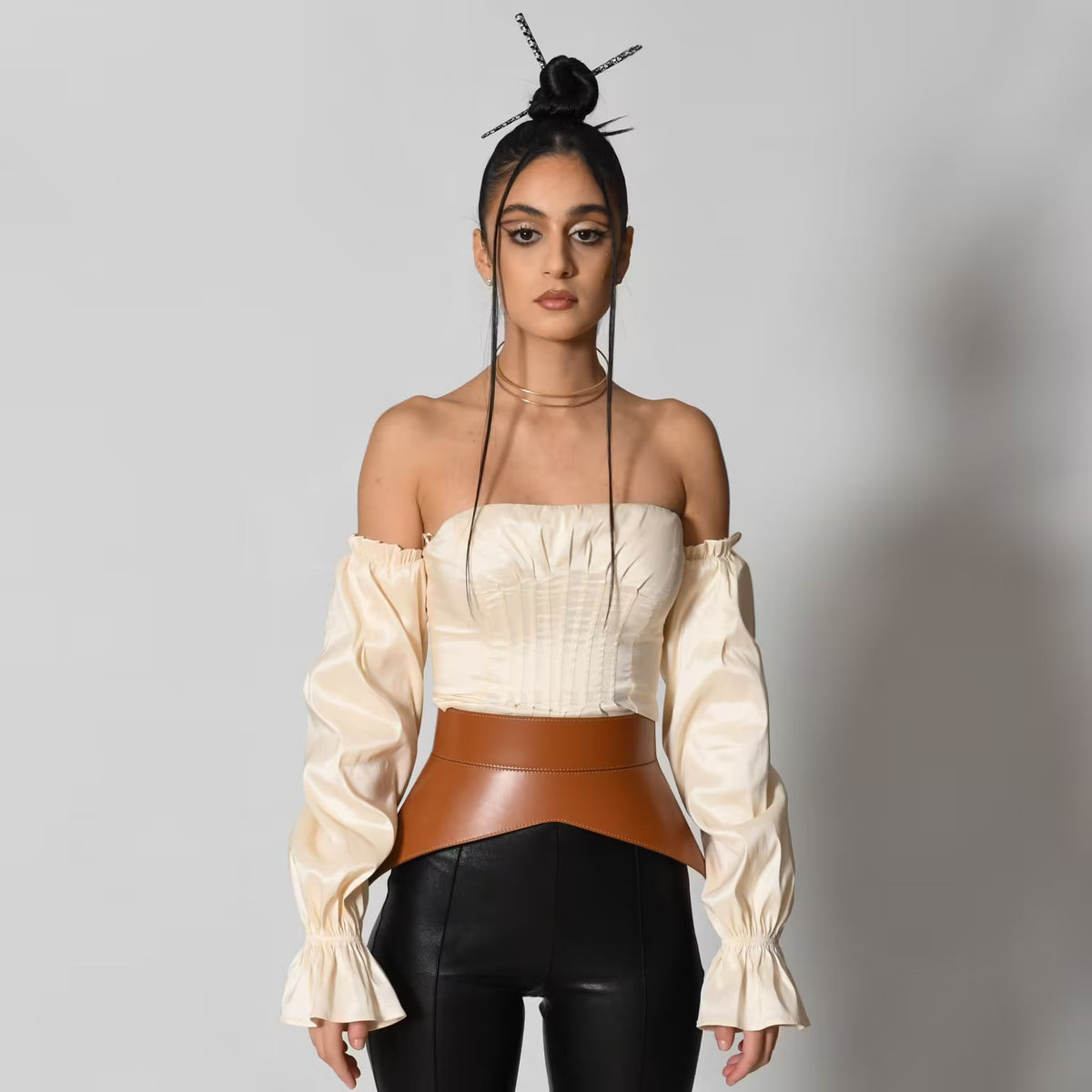 Aria Margo brown Italian leather peplum corset belt worn over a cream off-shoulder top and black trousers