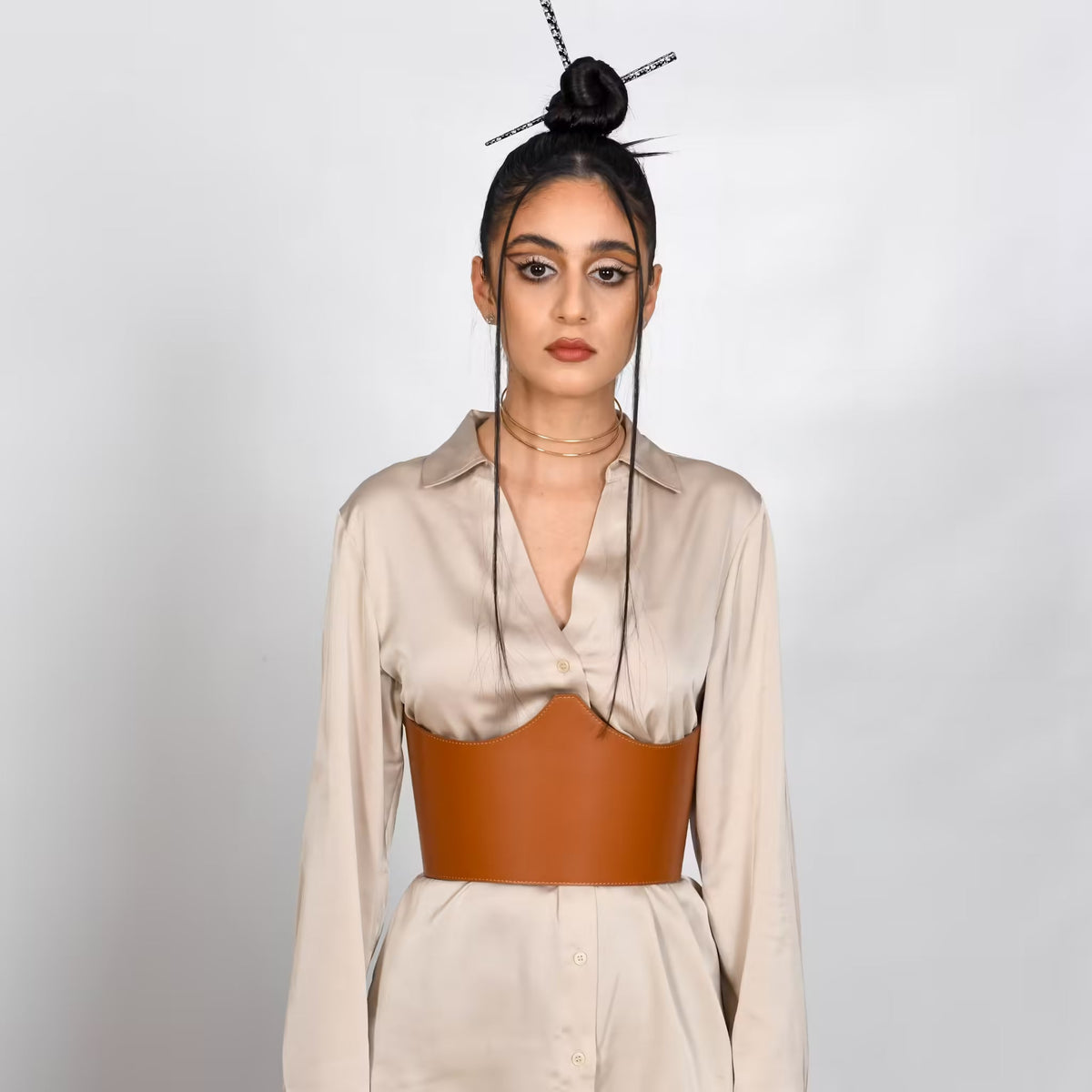 Aria Margo brown Italian leather under-bust belt worn over a beige silk shirt by a model with a high bun.