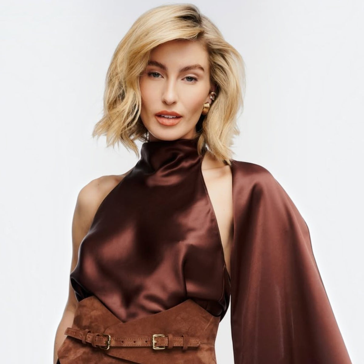 Aria Margo brown suede Thorns corset belt worn over a dark satin top, highlighting a pointed waist silhouette.