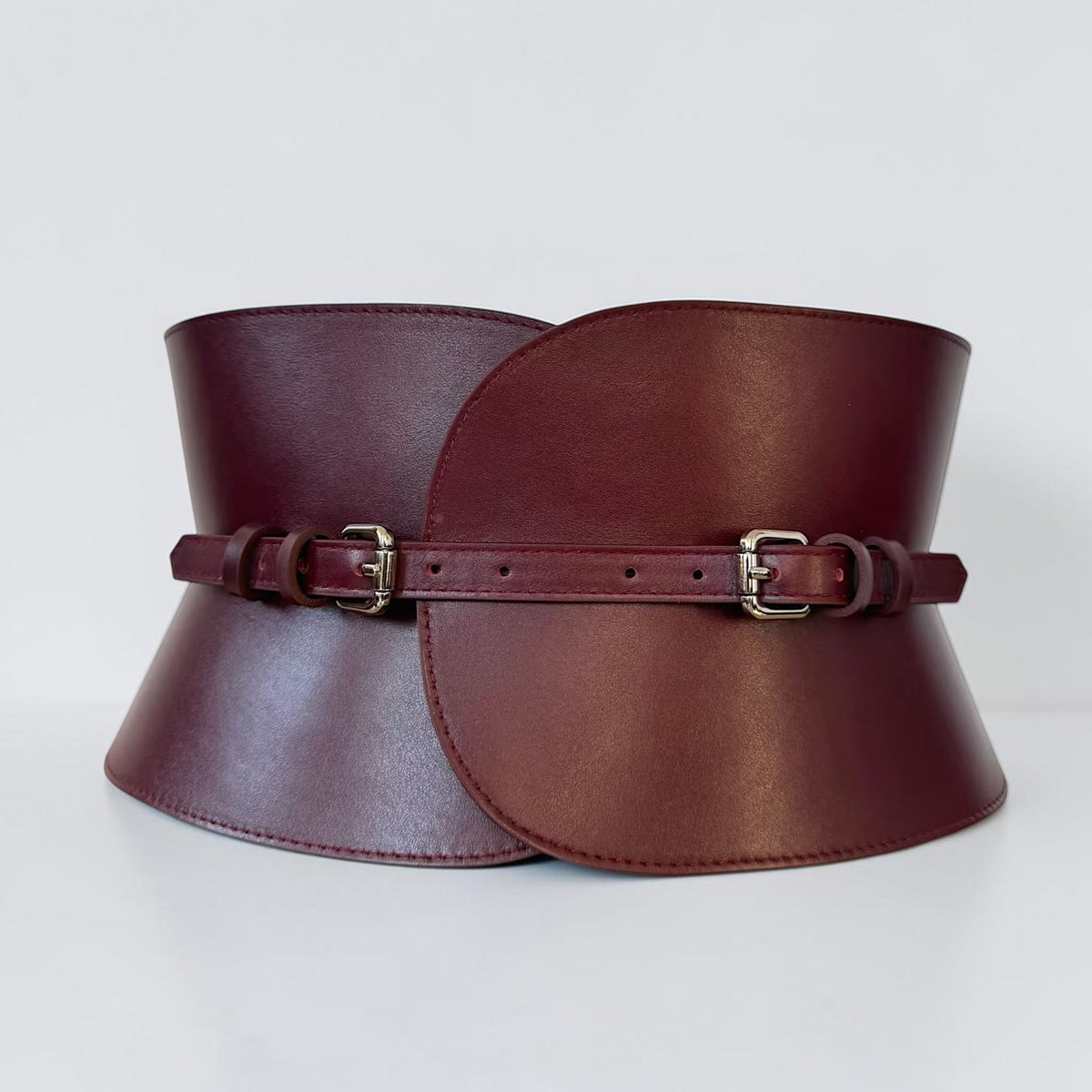 Aria Margo burgundy leather V-cut corset belt with an hourglass silhouette and two adjustable metal buckles.