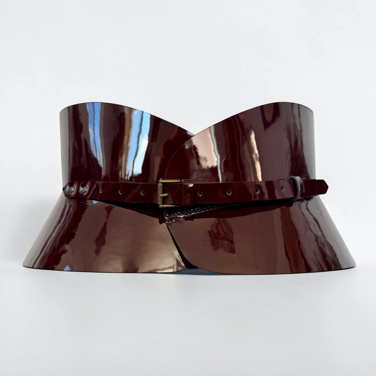 Aria Margo chocolate brown patent leather hourglass corset belt with a slim buckle on a marble surface.