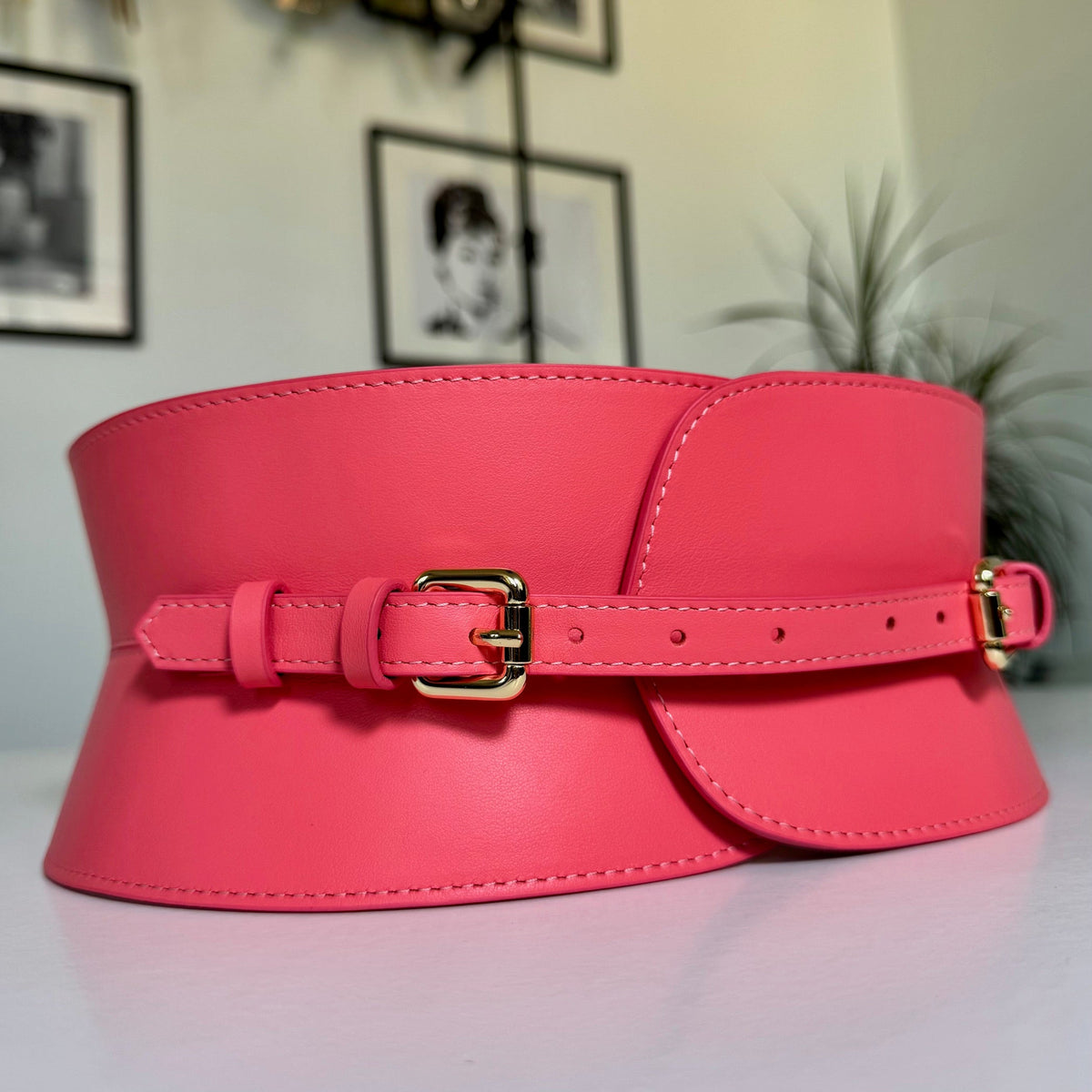 Aria Margo coral pink Italian leather corset belt with a gold buckle and adjustable strap on a white surface.