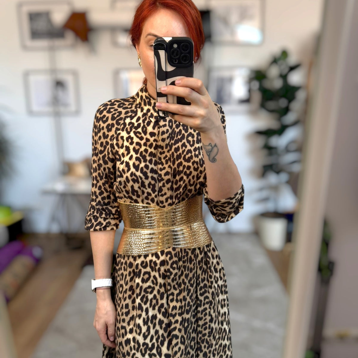 Aria Margo gold croc-embossed leather hourglass corset belt worn over a leopard print dress in a mirror selfie.