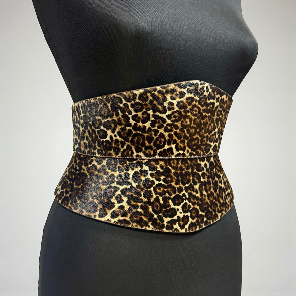 Aria Margo leopard print pony-hair leather corset belt with an hourglass silhouette on a mannequin torso.